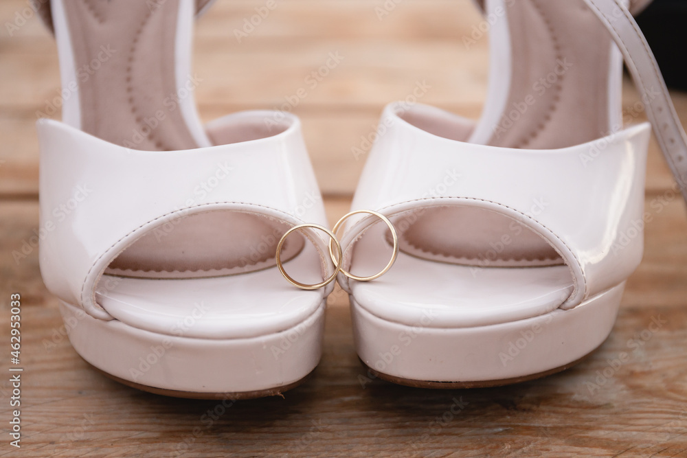 Obraz premium Engagement rings on a wooden background in front of the shoes