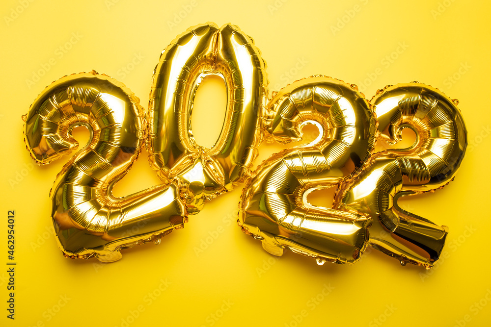2022 New Year Concept from golden foil balloon on yellow background 2022 New Year Concept from golden foil balloon on yellow background