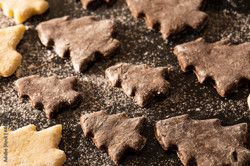 Pre-baked vanilla and chocolate Christmas cookies dusted with flour on the baking sheet Pre-baked vanilla and chocolate Christmas cookies dusted with flour on the baking sheet