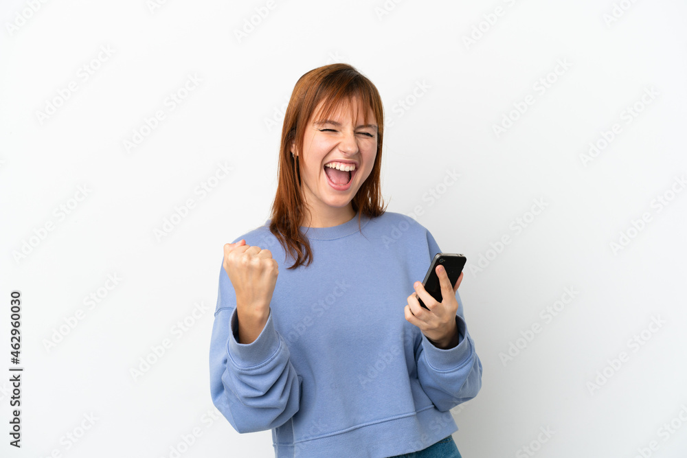 Redhead girl isolated on white background with phone in victory position Redhead girl isolated on white background with phone in victory position