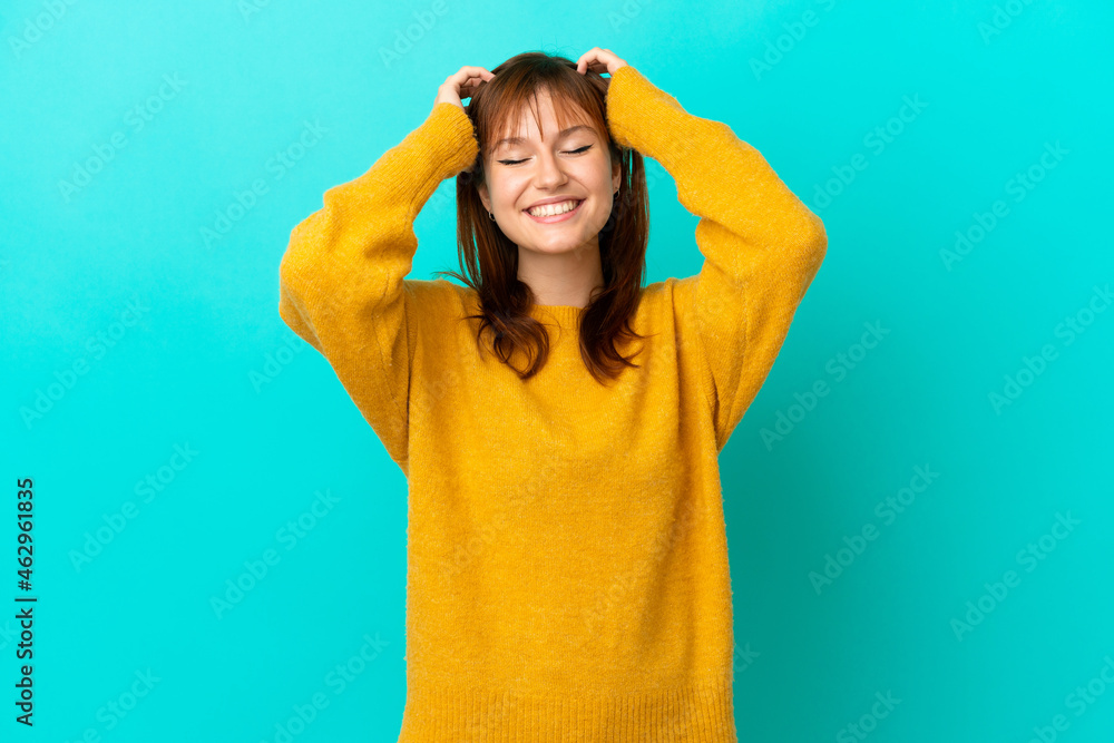 Redhead girl isolated on blue background laughing Redhead girl isolated on blue background laughing