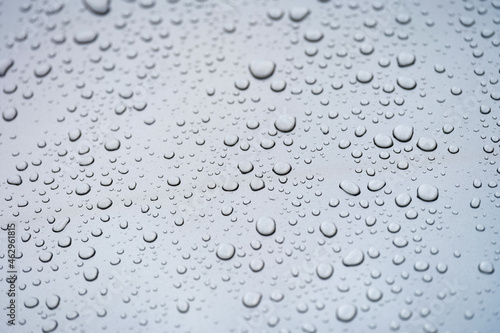 Raindrops on glass against gray sky closeup