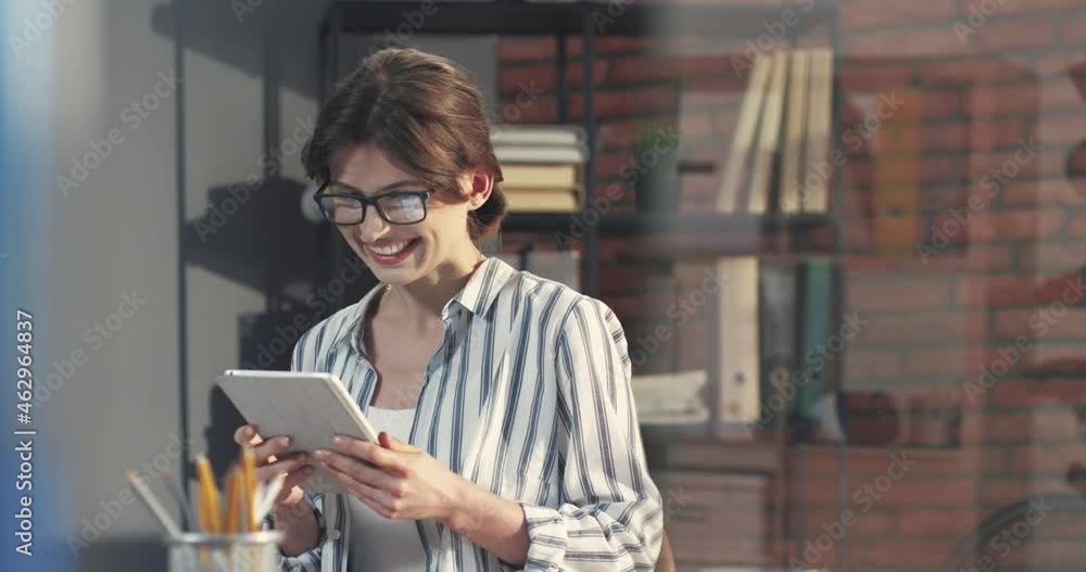 Young beautiful business woman sitting in office with tablet and rejoices at good news and work on new project. Young beautiful business woman sitting in office with tablet and rejoices at good news and work on new project.