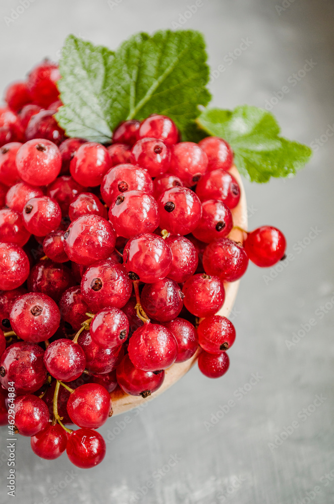 Juicy fresh currants in a wooden spoon on a light background. Copy space.