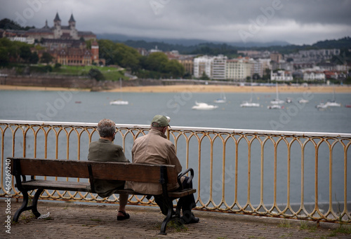 Una pareja de señores mayores de espaldas sentados en un banco mirando el mar en San Sebastian, Pais vasco. 