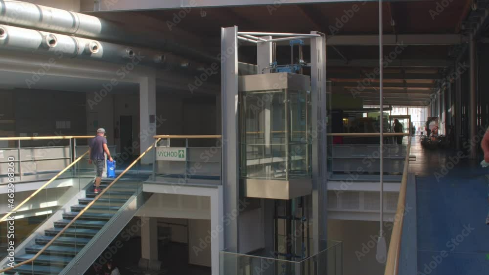 A staircase in a large room. Moving a person between levels. Glass elevator. Pipes on the ceiling, ventilation system of the mansion. A staircase in a large room. Moving a person between levels. Glass elevator. Pipes on the ceiling, ventilation system of the mansion.