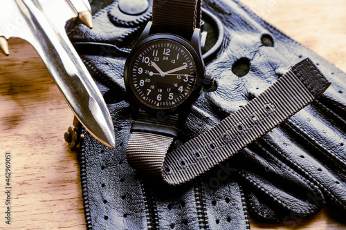 watch with a black and extendable canvas in the same tone along with motorcycle-style leather gloves and a metal plane ornament.