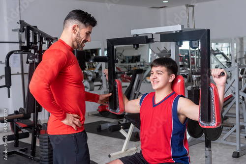 gym teacher teaching a student to do their exercises and train in a gym with machines and weights for a healthy life photo