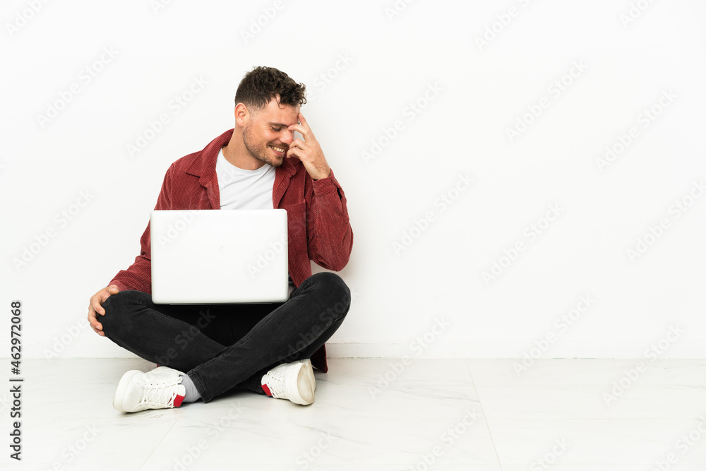 Young handsome caucasian man sit-in on the floor with laptop laughing Young handsome caucasian man sit-in on the floor with laptop laughing