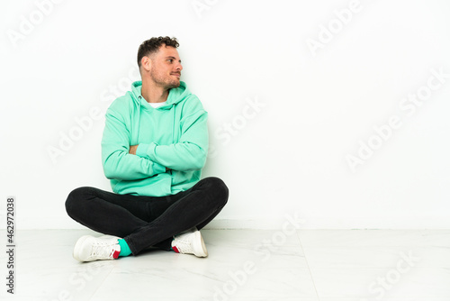 Young handsome caucasian man sitting on the floor in lateral position