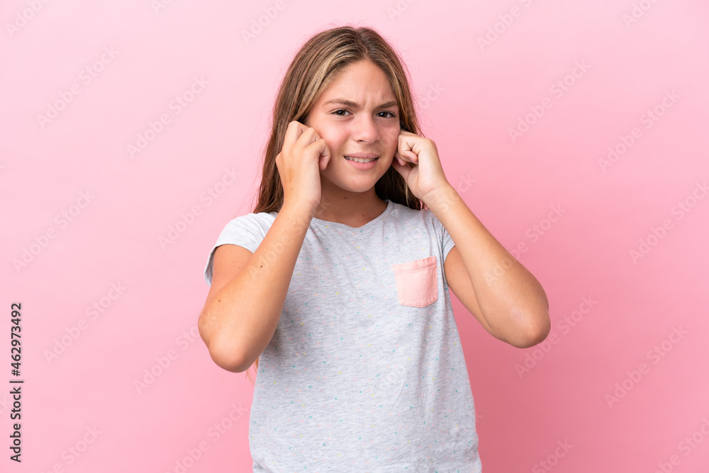 Little caucasian girl isolated on pink background frustrated and covering ears
