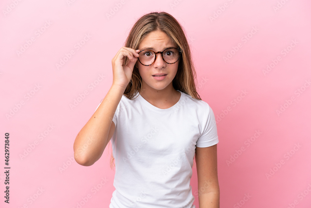 Little caucasian girl isolated on pink background With glasses and frustrated expression