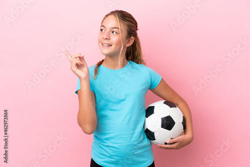 Little football player girl isolated on pink background pointing up a great idea