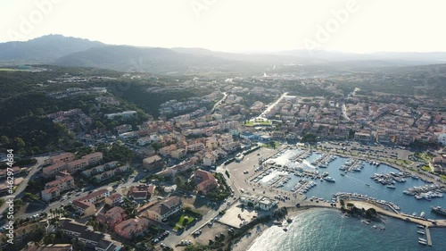 Sunset at the coastal village of Palau in northern sardinia. perfect for vacation, clear blue water. Boats and yachts anchored on the jetty. Drone aerial view sideways, Italy