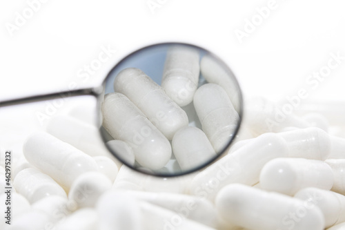 White capsules in the reflection of a dental mirror isolated on white background.