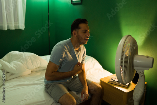 Hispanic man turning on the fan at night
