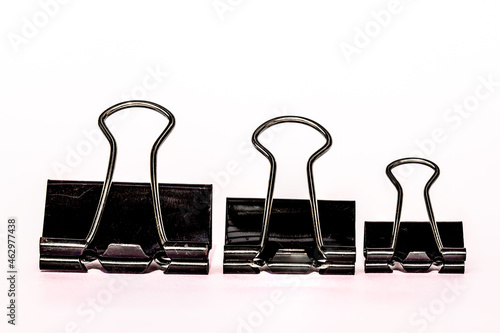 Three black metal paper clips, isolated with a white background