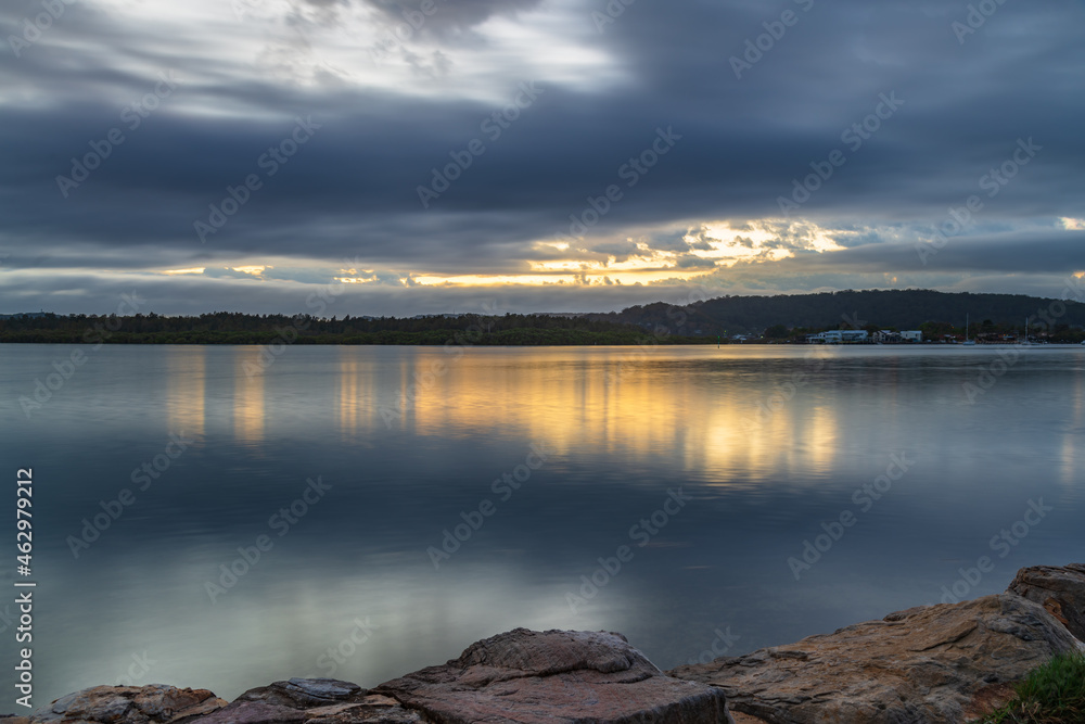 Sunrise waterscape with cloud covered sky