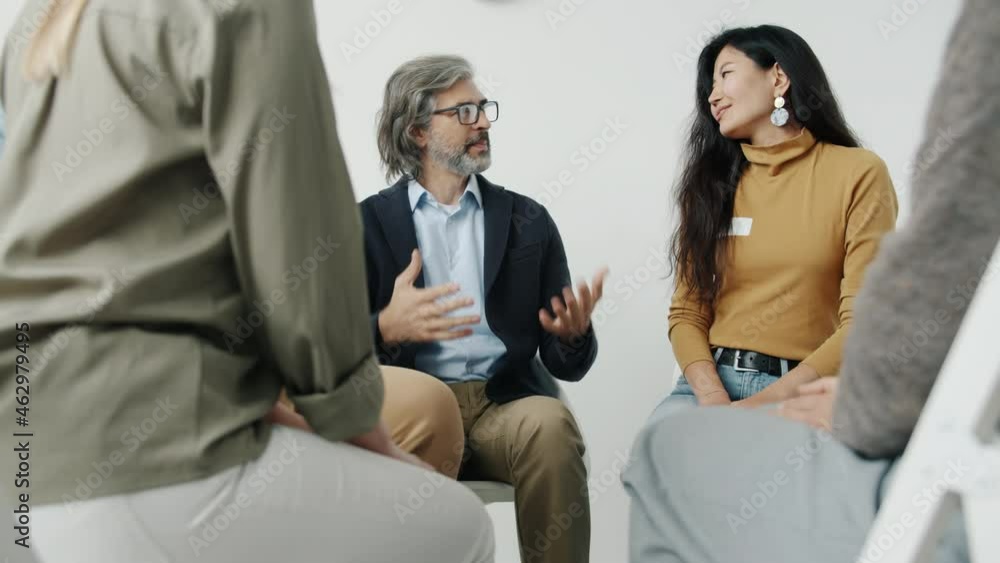 Portrait of people holding hands talking and smiling during group therapy meeting indoors in light studio. Psychology and communication concept. Portrait of people holding hands talking and smiling during group therapy meeting indoors in light studio. Psychology and communication concept.