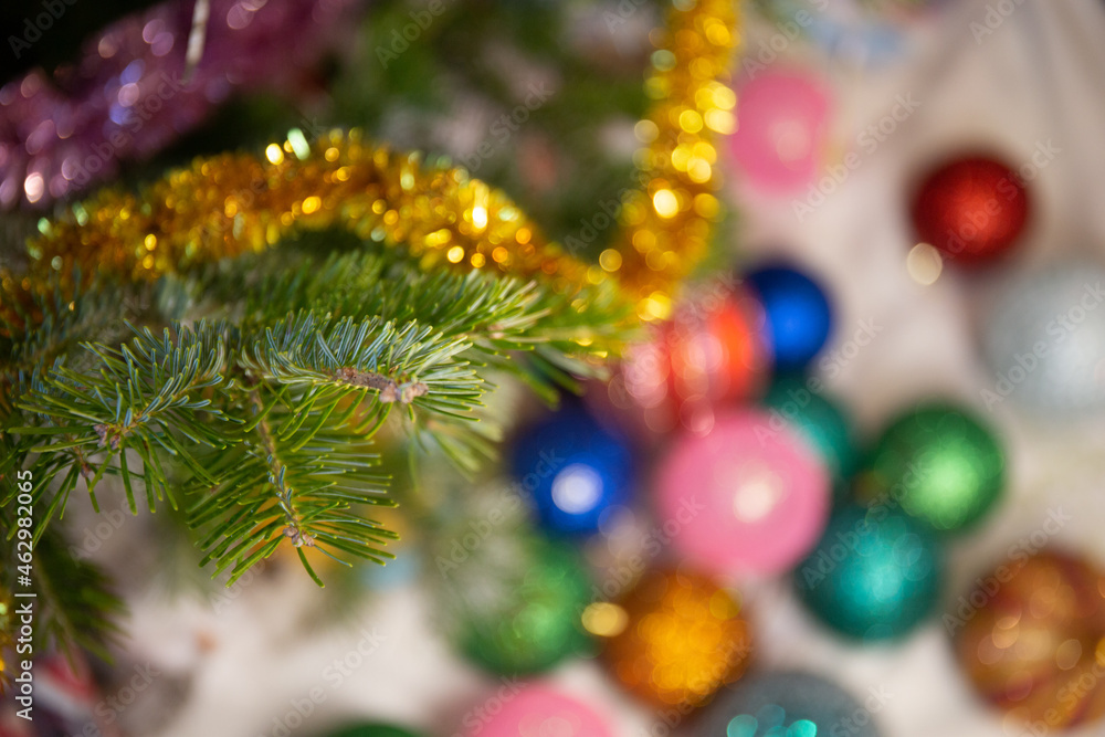 Blurred Christmas balls lie on the floor under the tree. Fir branches in focus. Holiday concept, new year, christmas.