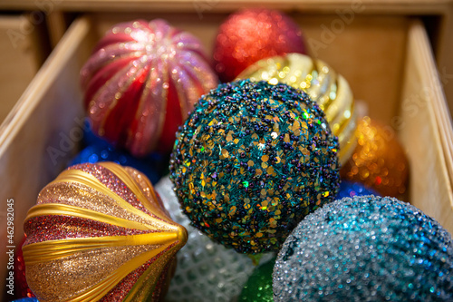 Beautiful multi-colored Christmas balls lie in a wooden box. Preparing for the new year and christmas. Large shiny balls.