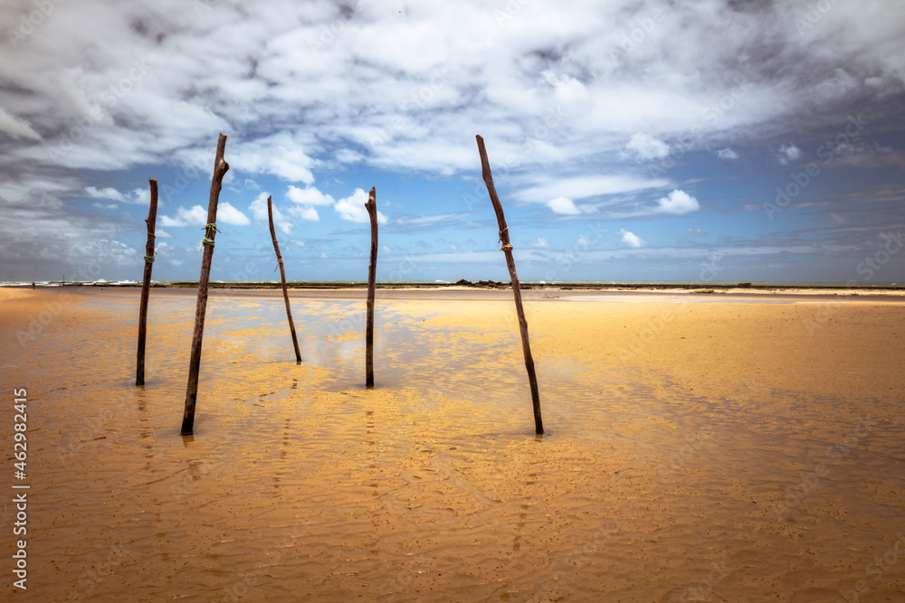 Four wooden posts on the beach during a stormy day. Deserted beach