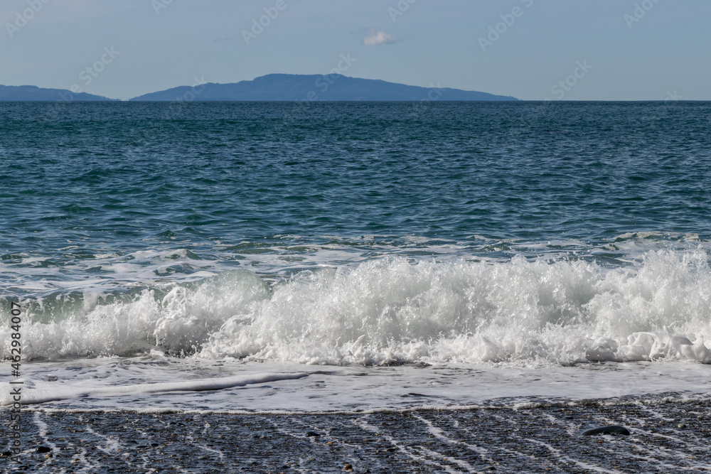 Waves on the beach with mountains on the horizon at Sombrio Beach on Vancouver Island