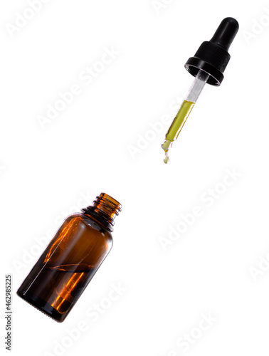 A bottle of cannabis oil and a dropper falling down isolated in white background
