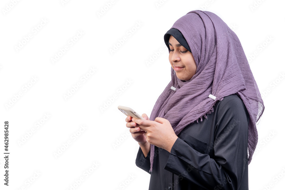 Asian Muslim teenage girl standing talking on a mobile phone with a happy face, on white background. Asian Muslim teenage girl standing talking on a mobile phone with a happy face, on white background.