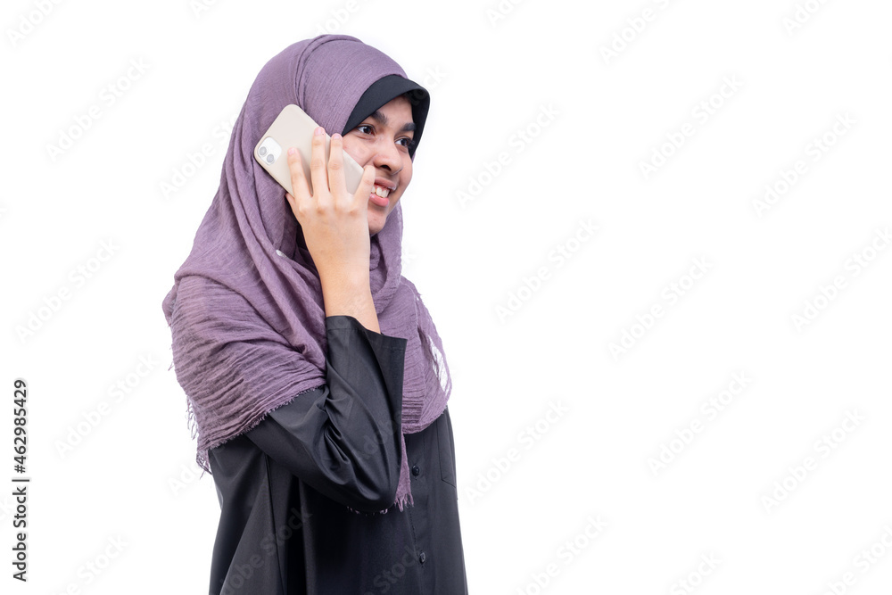 Asian Muslim teenage girl standing talking on a mobile phone with a happy face, on white background.