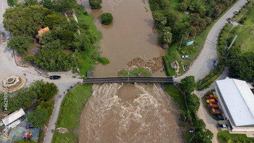 Aerial view of Rama 6 Dam (Phra Narai Gate) in Thailand with powerful of water. During Flood disaster in Central of Thailand. Many buildings are submerged in water.