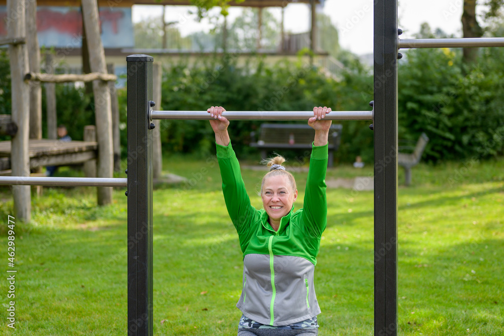 Fit woman having fun working out on bars in a park Fit woman having fun working out on bars in a park