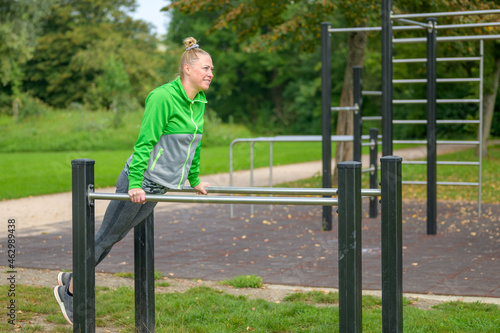 Athletic woman in her forties working out on parallel bars