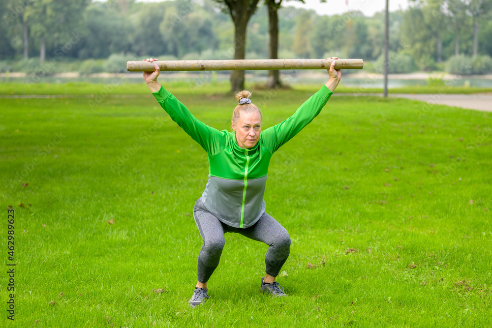 Fit muscular woman working out with a bar of wood in a field Fit muscular woman working out with a bar of wood in a field