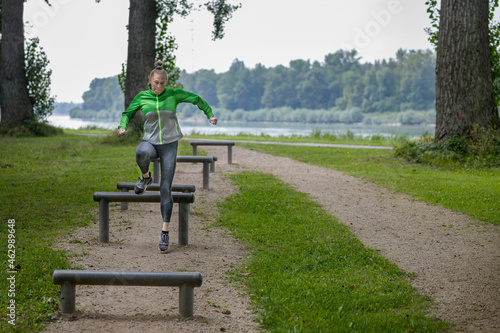 Fit sporty woman jumping hurdles in a wooded park