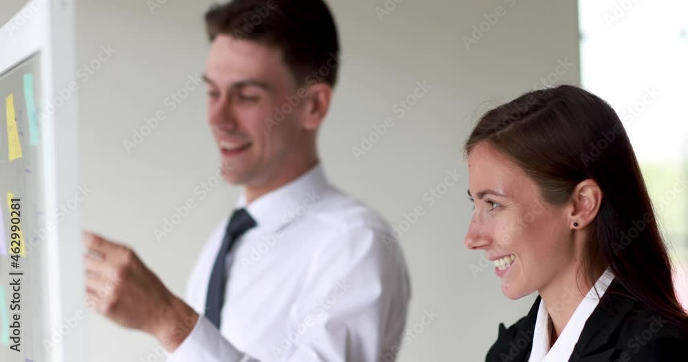 Businessman and businesswoman colleague standing for review and analysis information on paper stick note on clear glass board. Businessman and businesswoman colleague standing for review and analysis information on paper stick note on clear glass board.