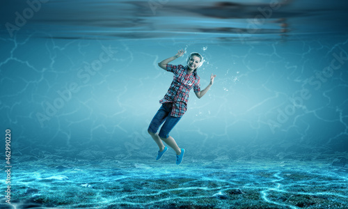 Woman wearing headphones underwater . Mixed media
