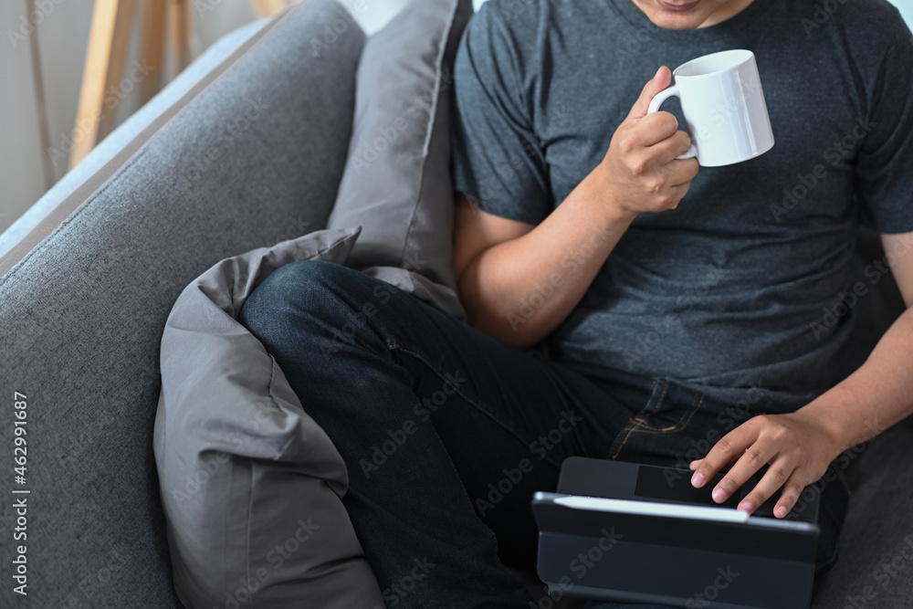 Young man drinking coffee and reading email on computer tablet. Young man drinking coffee and reading email on computer tablet.