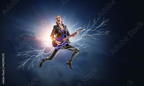 Young and beautiful rock girl playing the electric guitar