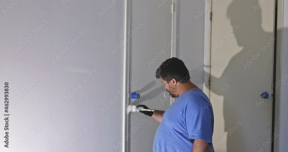 Home renovation in the handyman paints with a layer of white color paint brush a door frame Home renovation in the handyman paints with a layer of white color paint brush a door frame