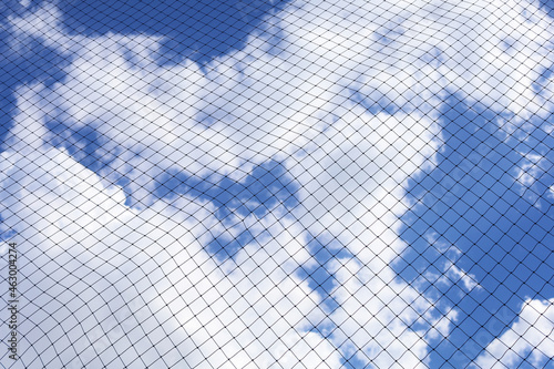 Low angle view of mesh against cloudy blue sky