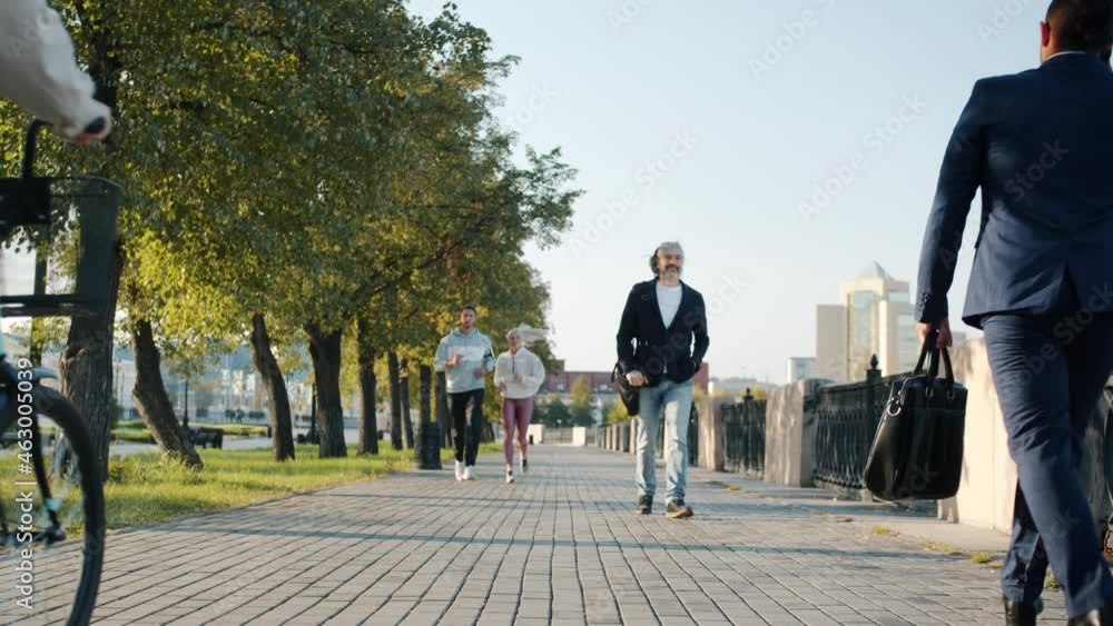 Slow motion of people diverse group moving in city street walking riding bike jogging on sunny summer day. Urban lifestyle and summertime concept. Slow motion of people diverse group moving in city street walking riding bike jogging on sunny summer day. Urban lifestyle and summertime concept.