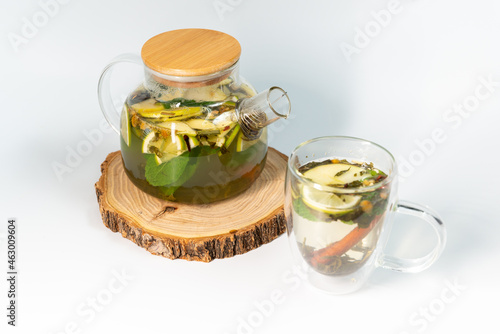 Moroccan tea in a transparent teapot on a white background next to a filled transparent mug