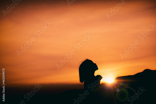 young girl standing praying with light of sunset background  christian silhouette concept.