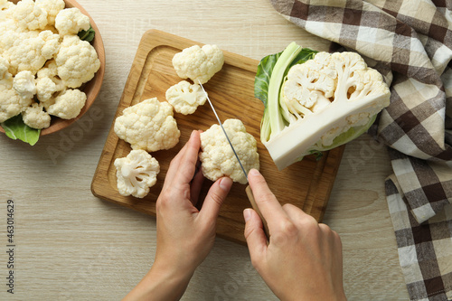 Female hands cut cauliflower on wooden board photo