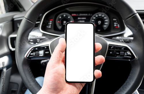 Driver hand using smartphone in car. Smartphone in a car use for Navigate or GPS. Mobile phone with isolated white screen. Blank empty screen. copy space. Empty space for text. © Aleksei