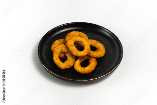onion rings on a black plate on a white background