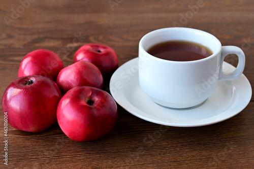 Autumn composition of red apples lying on wooden table and white cup of tea. Concept of home comfort and warmth. Hello, September!