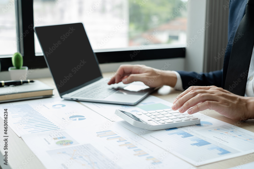 The hand of businessman sit at their desks and calculate financial graphs showing results about their investments, plan a successful business growth process The hand of businessman sit at their desks and calculate financial graphs showing results about their investments, plan a successful business growth process