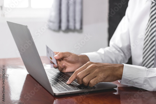 The businessman's hand is holding a credit card and using a laptop for online shopping and internet payment © Orathai